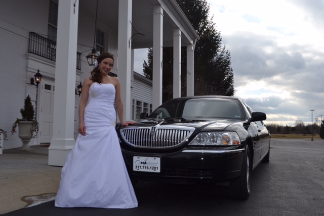 Woman in wedding dress in in front of stretch limo 