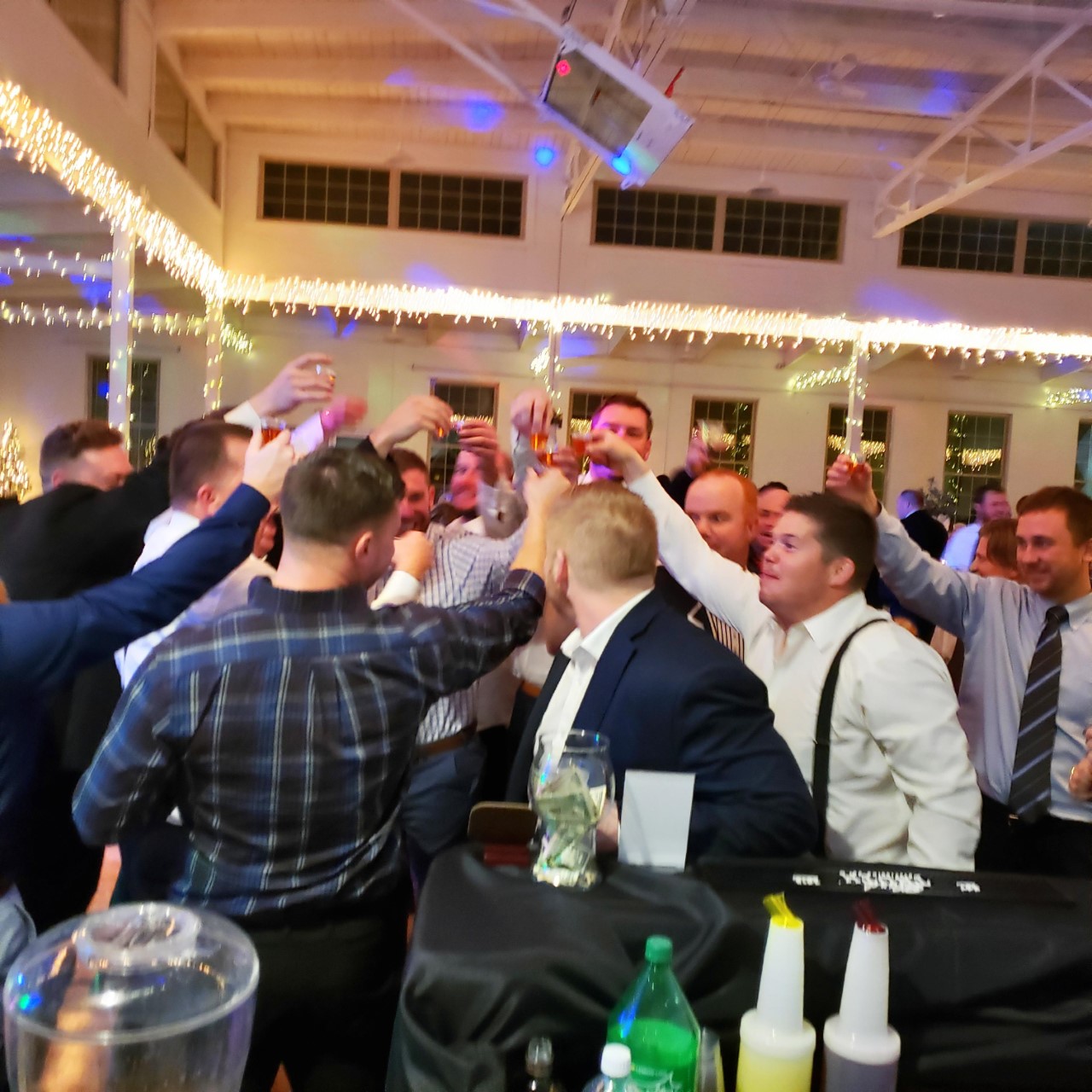 Group of individuals cheers on gym floor at wedding