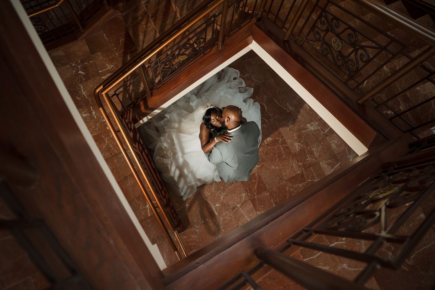 Photo Credit belongs to Ralph Vandale Photo taken inside 3 story tower at community life center wedding venue. Beautiful couple at bottom of stair well, photo taken at second level looking down