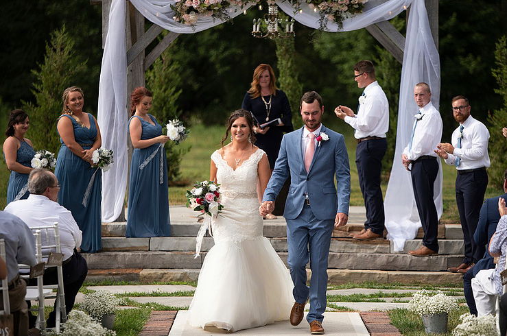 Husband and wife walking back down asile after exchanging vows. At venue Crystal Coop in Anderson Indiana