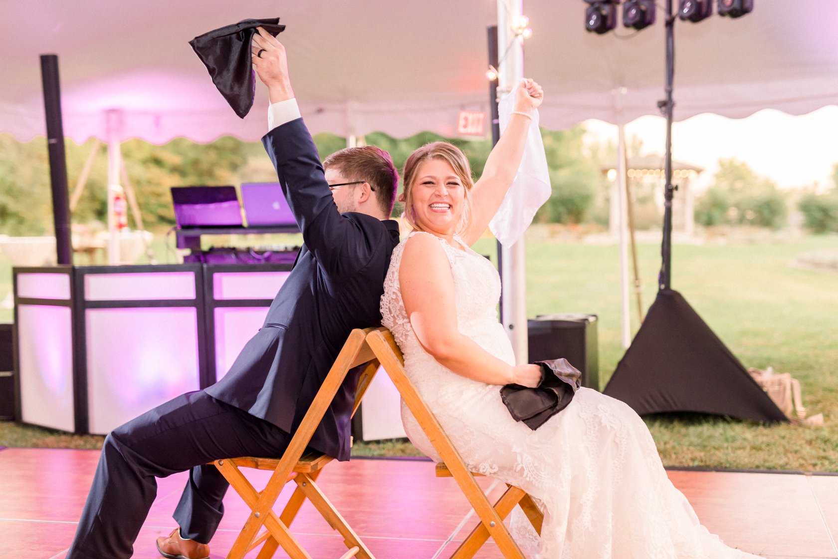 Couple playing the newly wed game, Male in suit and tie holding up black napkin, femal in white wedding dress holding in air white napkin